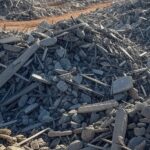 Escombros do Torre Palace Hotel após implosão em Brasília, com máquinas iniciando limpeza de destroços.