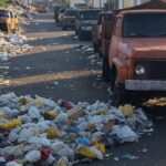 Rua no Gama com lixo acumulado, caminhões estacionados e sinais de pragas urbanas, destacando caos sem ação das autoridades.