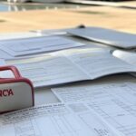 Mesa com formulários de concursos no DF e kit de primeiros socorros, simbolizando nova lei complicadora.