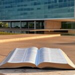 Edifício da CLDF em Brasília com Bíblia aberta, representando reconhecimento como patrimônio e debate sobre laicidade.