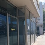 Fachada de agência bancária no Brasil reabrindo com portas abertas e sinal de funcionamento após feriados.