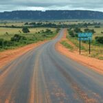 Vista da fronteira Brasil-Venezuela em Pacaraima, com placa de divisa e estrada vazia, alertando para riscos após captura de Maduro.