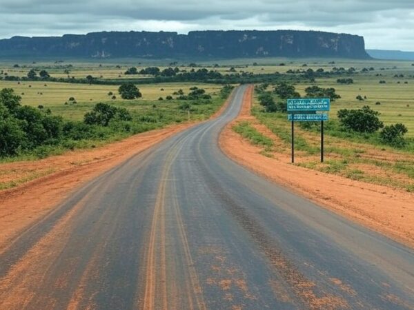 Vista da fronteira Brasil-Venezuela em Pacaraima, com placa de divisa e estrada vazia, alertando para riscos após captura de Maduro.