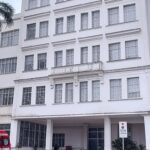 Hospital na Bahia com ambulância, simbolizando intoxicação por metanol e internações.