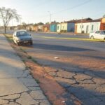 Rua em Ceilândia com marcas de arrasto no asfalto e carro abandonado, representando agressão e fuga de agressor.