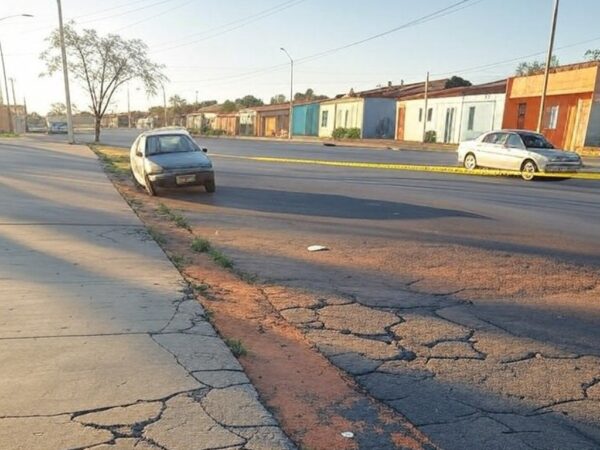 Rua em Ceilândia com marcas de arrasto no asfalto e carro abandonado, representando agressão e fuga de agressor.