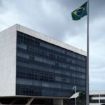 Prédio do Tribunal de Justiça em Brasília com bandeira a meio mastro, simbolizando luto pela morte de desembargador.