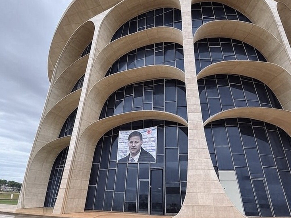 Fachada da CLDF em Brasília com banner vazio, ilustrando frustração por anúncio vago de concurso fotográfico.