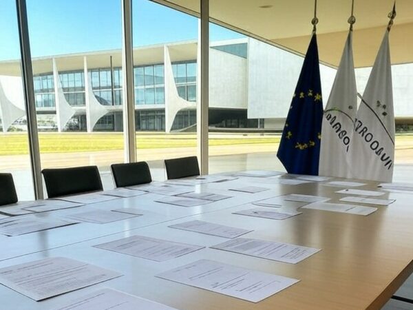 Mesa de conferência com bandeiras da UE e Mercosul em Brasília, representando acordo histórico de livre-comércio.