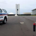 Viatura da PMDF em Brasília com lata de spray de pimenta no chão, ao fundo o Congresso Nacional.