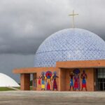 Templo religioso em Brasília com Câmara Legislativa ao fundo, representando isenção de taxas e críticas por privilégios fiscais.
