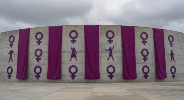 Edifício da CLDF em Brasília decorado com faixas roxas para o 8 de Março, mascarando violência contra mulheres em desfile.