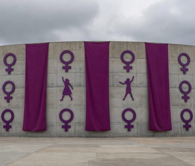 Edifício da CLDF em Brasília decorado com faixas roxas para o 8 de Março, mascarando violência contra mulheres em desfile.