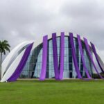 Fachada da CLDF em Brasília com símbolos da Semana da Mulher sob céu nublado, destacando críticas ao impacto real no DF.