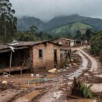 Paisagem de casas danificadas por tragédia na Zona da Mata Mineira, com montanhas e vegetação ao fundo.