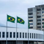 Fachada da CLDF em Brasília com hospital deteriorado ao fundo, expondo falhas na saúde do DF.