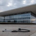 Hospital público deteriorado e viatura policial em rua mal conservada em Brasília, ilustrando falhas na saúde e segurança do DF.