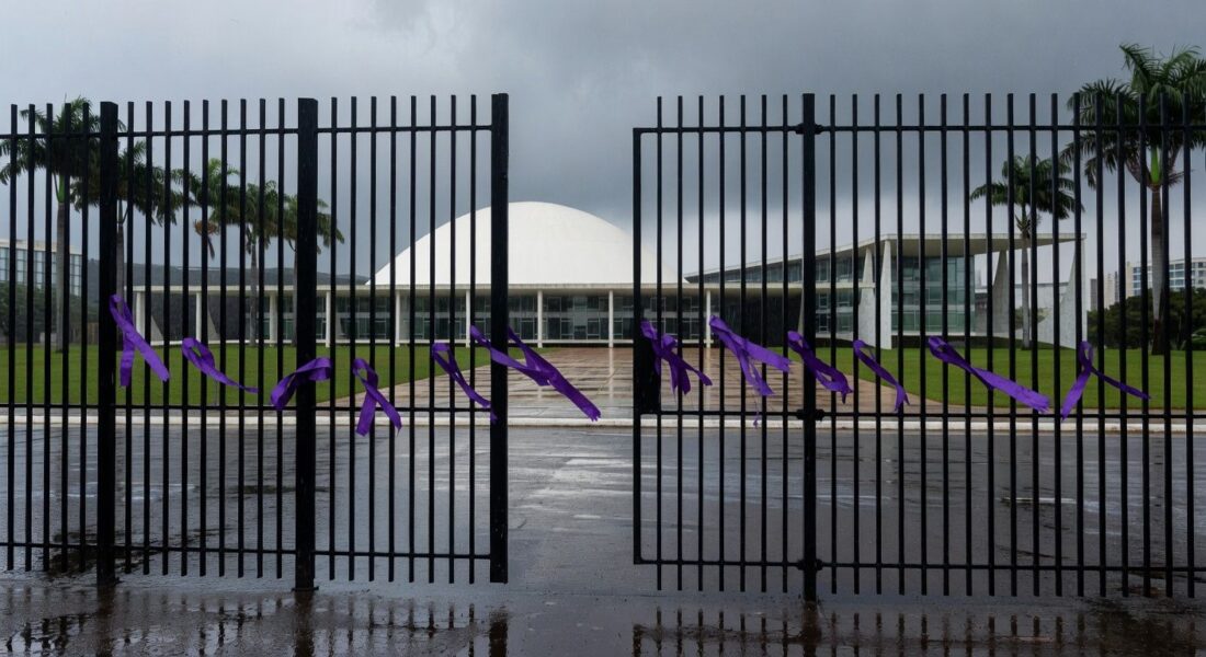 Edifício da CLDF em Brasília com símbolos contra violência de gênero, sob céu nublado, representando aumento alarmante de violência.
