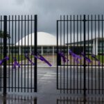 Edifício da CLDF em Brasília com símbolos contra violência de gênero, sob céu nublado, representando aumento alarmante de violência.