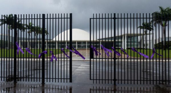 Edifício da CLDF em Brasília com símbolos contra violência de gênero, sob céu nublado, representando aumento alarmante de violência.