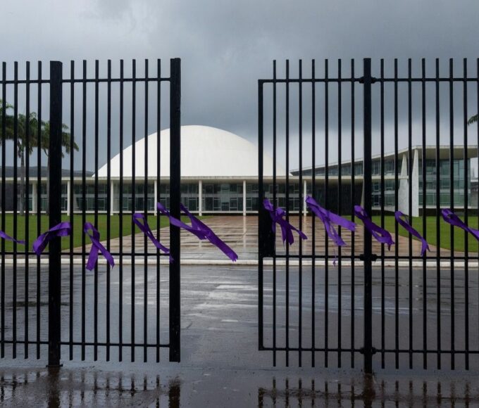Edifício da CLDF em Brasília com símbolos contra violência de gênero, sob céu nublado, representando aumento alarmante de violência.