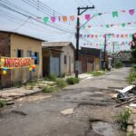 Rua no Riacho Fundo I com decorações de aniversário e problemas de infraestrutura urbana no Distrito Federal.