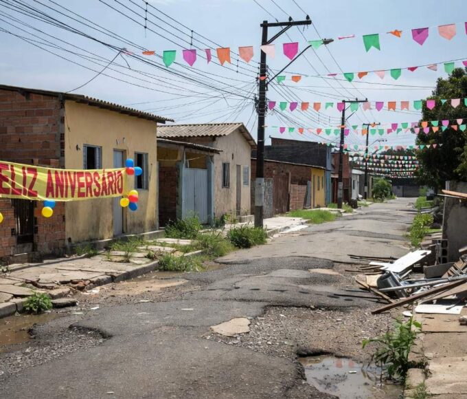 Rua no Riacho Fundo I com decorações de aniversário e problemas de infraestrutura urbana no Distrito Federal.