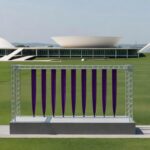 Estrutura de evento contra feminicídio em salão moderno de Brasília, com faixas roxas e arquitetura do DF ao fundo.