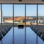 Sala de reuniões em Brasília com vista para edifícios de saúde e habitação, representando avanços governamentais.