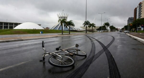 Cena de acidente de trânsito em rua de Brasília com bicicleta caída e marcas de pneus, representando atropelamento fatal de ciclista no DF.