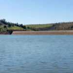 Reservatório de água no DF atingindo capacidade máxima, evitando racionamento, com barragem e paisagem do cerrado.