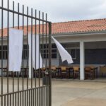 Escola pública em Brasília com portões fechados e faixas de greve, representando paralisação de professores no DF.