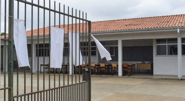 Escola pública em Brasília com portões fechados e faixas de greve, representando paralisação de professores no DF.