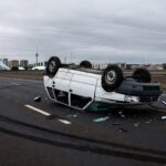 Carro Fiat Uno capotado em acidente na DF-005 em Brasília, com destroços no asfalto.