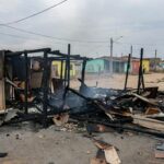 Barraco carbonizado após incêndio em Ceilândia, com cinzas e fumaça residual em rua periférica.