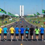 Maratona em Brasília celebrando 66 anos da cidade, com vista do Eixo Monumental e monumentos icônicos.