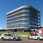 Edifício em Brasília representando centro de atendimento a profissionais de segurança, com viaturas estacionadas.